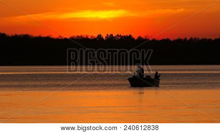 Silhouette Of Father And Son Fishing On Lake Irving At Sunset In Bemidji, Minnesota.