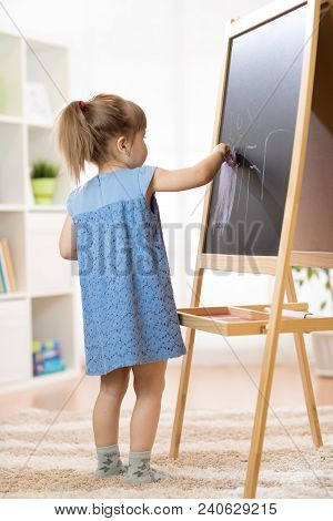 Child Girl Painting At Easel In School.