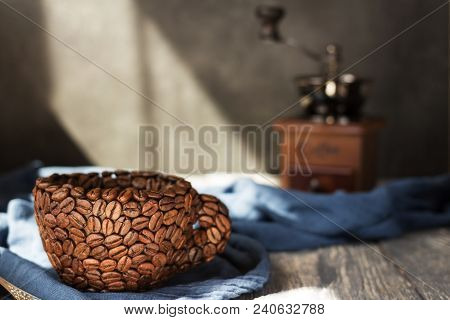 An Impromptu Cup Of Coffee Beans, Manual Coffee Grinder On Background Of Blue Fabric