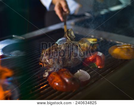Master chef cooking delicious grilled meat steak with vegetables on a barbecue