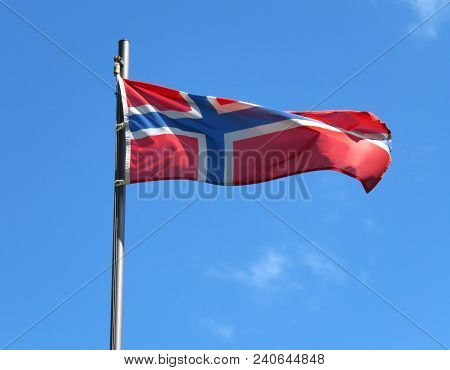 National Flag Of Norway On A Flagpole In Front Of Blue Sky.