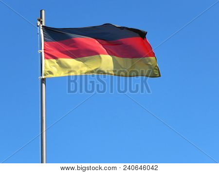 National Flag Of Germany On A Flagpole In Front Of Blue Sky.