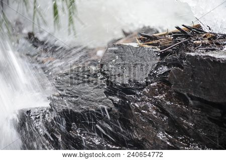 Water Cascading Off Jagged Rocks Along Edge Of Stream