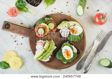 Summer Sandwiches With Fresh Vegetables, Eggs, Avocado, Tomato, Rye Bread On Light Marble Table. Top