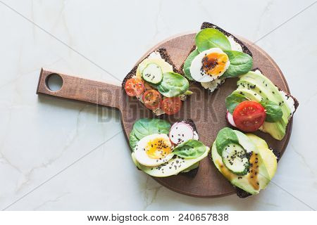 Different Sandwiches With Vegetables, Eggs, Avocado, Tomato, Rye Bread On Light Marble Table. Top Ve