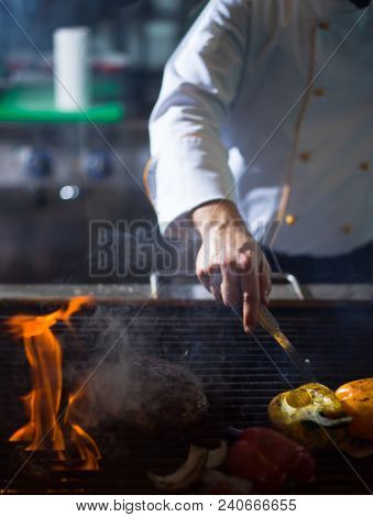 Master chef cooking delicious grilled meat steak with vegetables on a barbecue