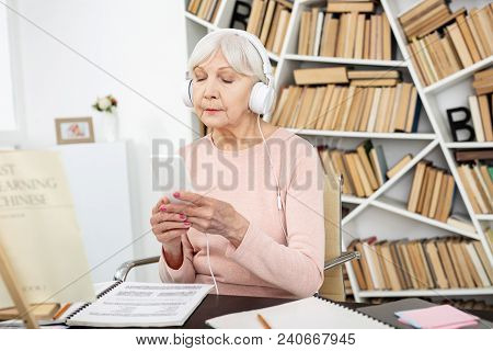 Listen Carefully. Concentrated Mature Woman Listening To Audio And Using Phone