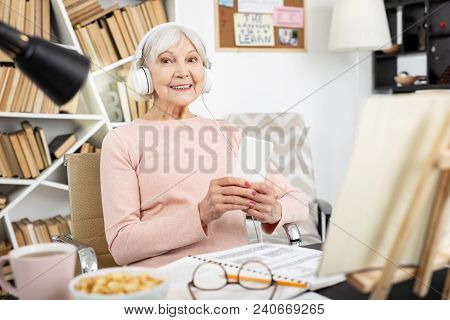 Native Speakers Speech. Gay Mature Woman Listening To Audio And Staring At Camera