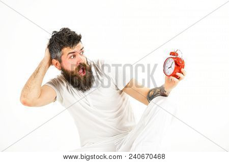 Hipster With Beard And Mustache Overslept. Man With Shocked Face Sits, Holds Alarm Clock. Man Needs 