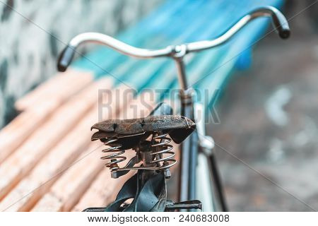 An Old Bicycle Seat With A Spring Shock Absorber. Vintage Bicycle On The Stone Wall Background.