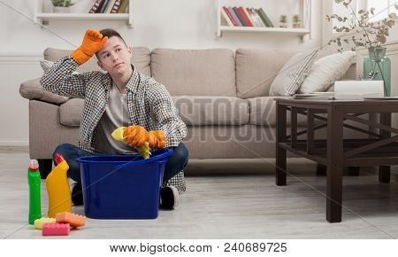 Tired Man Cleaning Home With Towel And Detergents In Living-room. Housekeeping And Tudying Up Concep
