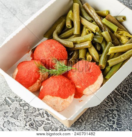 Boiled String Beans And Fish Balls In Sauce In A Lunchbox On A Gray Background. Healthy Food Deliver