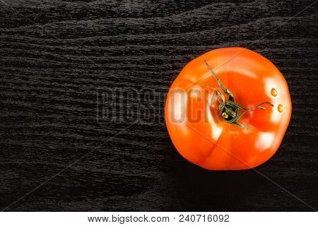 One Red Tomato Isolated On Black Wood Background Top View