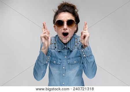 Young Girl In Black Cat Glasses On A Gray Background. Portrait Of A Young Beautiful Girl. Charming G