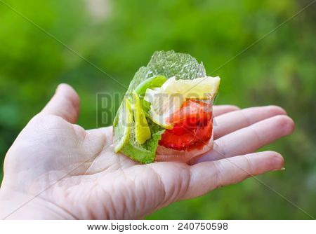 Melting Ice Cube With Strawberry, Lemon And Fresh Green Mint Leaves In A Hand