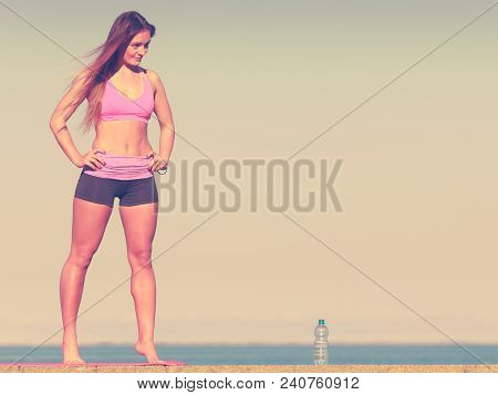 Woman In Sportswear Takes A Break To Rehydrate Drinking Water From Plastic Bottle, Resting After Spo