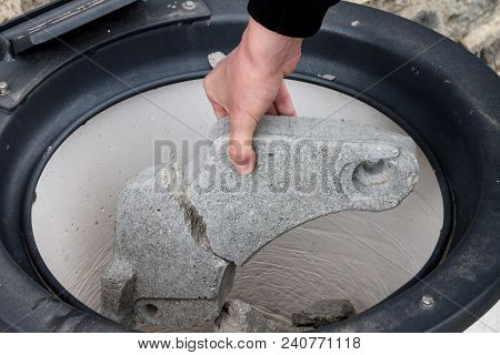 Throwing A Piece Of Concrete Into A Garbage Tank, The Hand Puts The Garbage Into The Trash Tank