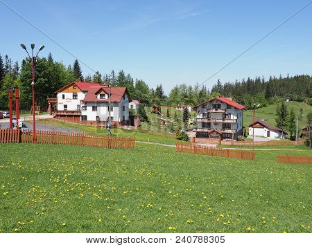 Salmopol, Poland On May 2018: Houses In Countryside Landscapes Of Grassy Field And Forest At Beskid 