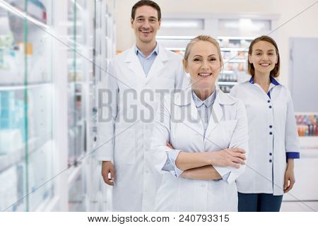 Come Here. Enthusiastic Three Pharmacists Smiling To Camera While Staying In Drugstore