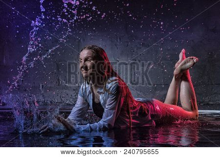 Girl In The White Shirt With Water Drop In A Dark Room Illuminated By Light During A Photoshoot With