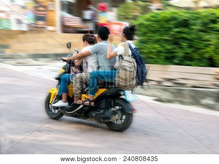 Three Young People On A Fast Motor Bike In Thailand Asia