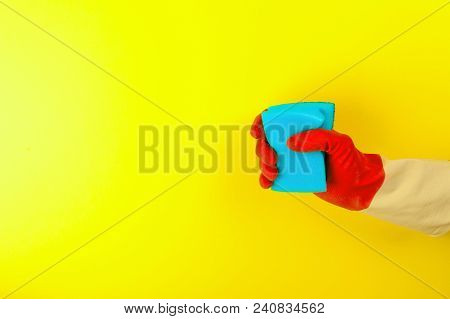 Hand Holding A Sponge For Dishes On Pastel Yellow Background