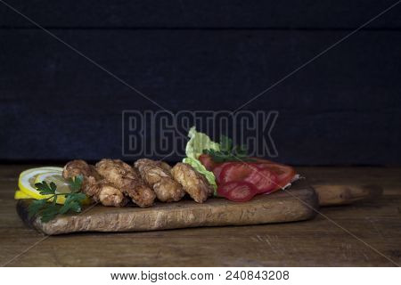Breaded Chicken Meat With Salad And Lemon Resting On A Rustic Wooden Board