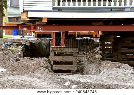An Old House Rests On Steel Girders  And Timbers As A New Concrete Basement Is Being Created.
Baseme