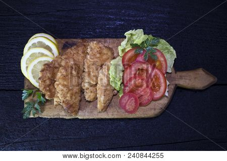 Breaded Chicken Meat With Salad And Lemon Resting On A Rustic Wooden Board