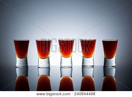 Small Glasses With A Drink Shots Of Alcohol Stainding In A Table With Reflection