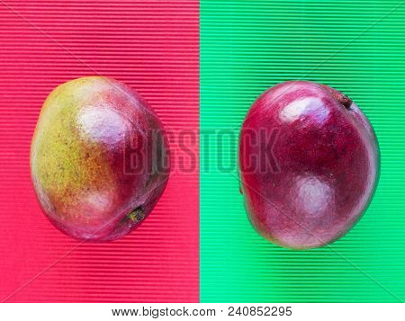 Red And Green Mango Fruits On The Corrugated Paper Of Opposite Color Background.