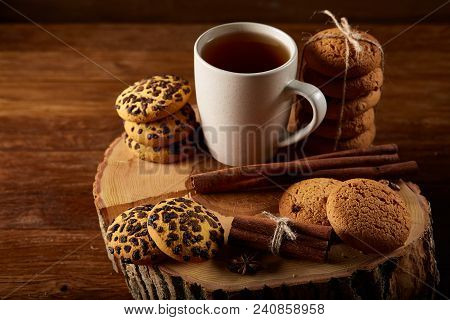 Christmas Concept With A Cup Of Hot Tea, A Large Set Of Cookies On A Homespun Napkin, Cinnamon Stick