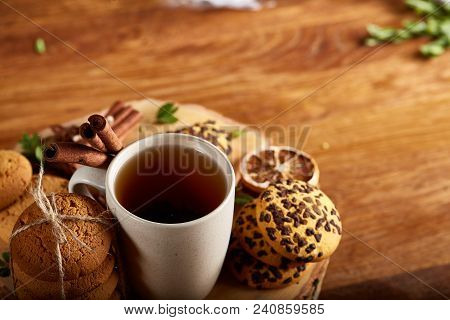 Christmas Concept With A Cup Of Hot Tea, A Large Set Of Cookies On A Homespun Napkin, Cinnamon Stick