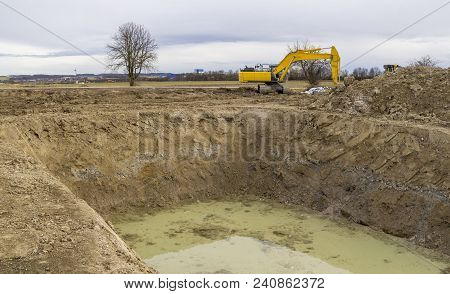 Excavator At A Big Hole Near A Loamy Construction Site