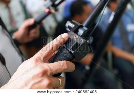 Close-up Of Working Camera Of Man Hand, Operator At Work. In The Hall Full Of Peoplestock Photo