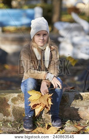 A Girl In Autumn Yellow Leaves In Sunset Rays