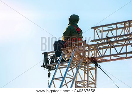 Industrial Climber In Uniform Sitting On A Building Structure. Alpinist Worker Checks His Equipment