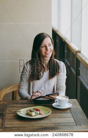 Woman Sitting Alone Near Big Window In Coffee Shop At Table With Cup Of Cappuccino, Cake, Relaxing I