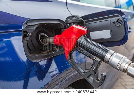 Fuelling Gun Inserted Into The Tank Of Blue Car At The Petrol Station