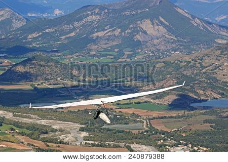 Hang Glider Flying In The Mountains Of The French Alps