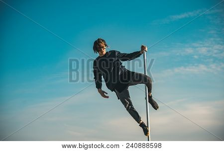Pole Dance Sport. Sexy Macho Man Fly On Blue Sky Background. Athletic Guy Make Acrobatic Elements On
