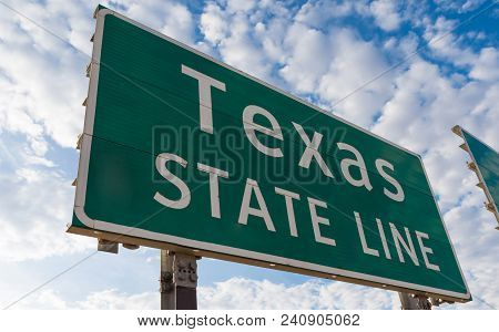 Texas State Line Road Sign In Front Of Cloudy Sky