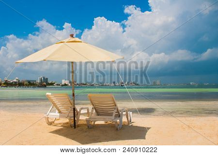 Sun Loungers And A White Umbrellas For Tourists On The Beach In Cancun. Mexico.