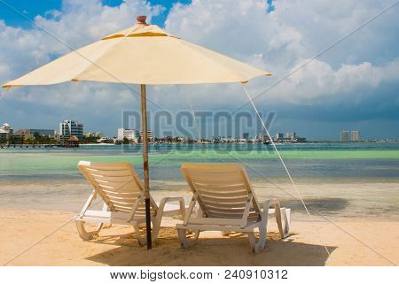 Sun Loungers And A White Umbrellas For Tourists On The Beach In Cancun. Mexico.