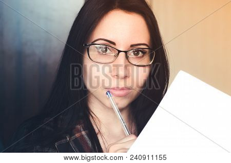 Young Woman With Glasses Holds A Pen And A Document. Concept Of Business Woman, Passing Exams, Tests