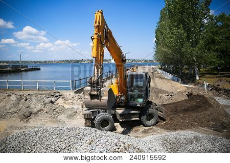 Big Excavator On New Construction Site. Excavator Loader Machine During Earthmoving Works Outdoors A
