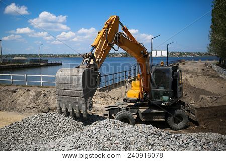 Big Excavator On New Construction Site. Excavator Loader Machine During Earthmoving Works Outdoors A