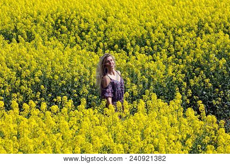 Blonde Girl On The Blooming Yellow Rapeseed Field