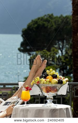 Retrato de mujer hermosa en la terraza, los pies sobre la mesa