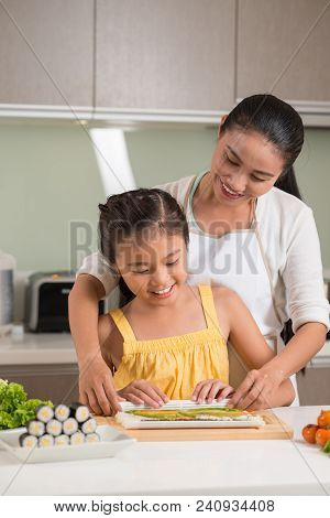 Cheerful Mother And Daughter Making Suchi Rolls